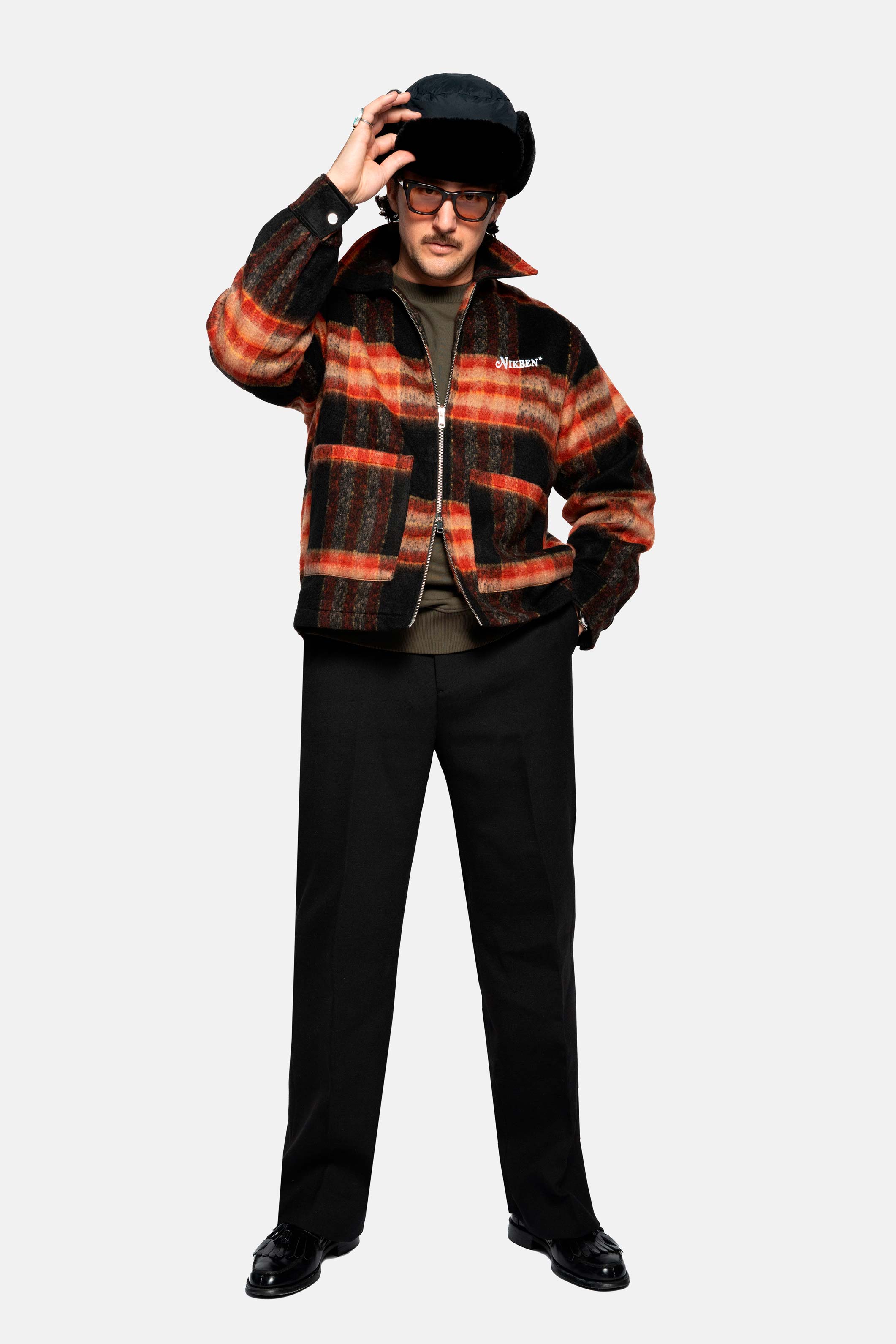 Male model wearing a orange red colored lumberjack jacket with pockets, full zipper and embroidered Nikben logo 