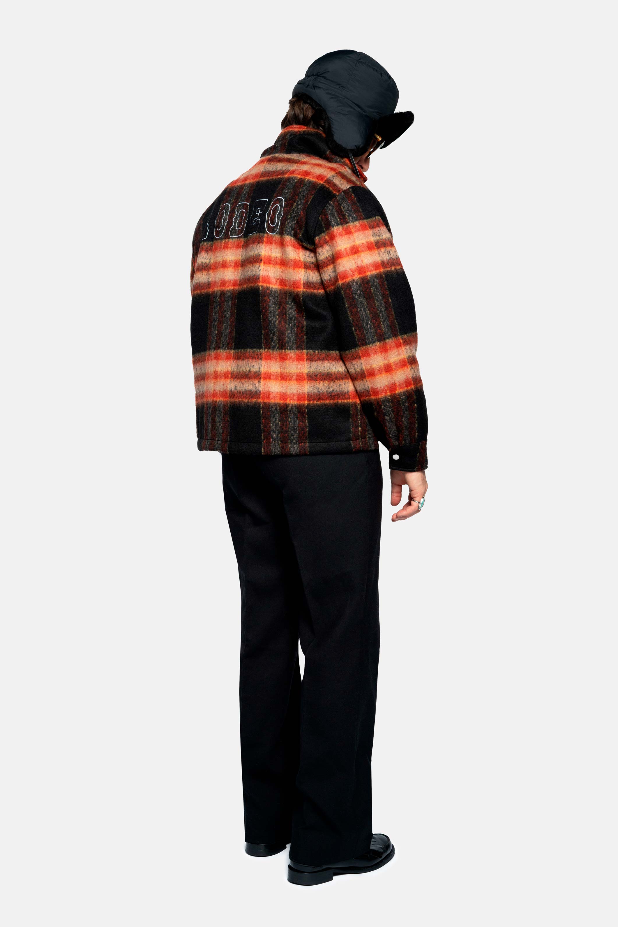 Back of male model wearing an orange red colored lumberjack jacket with pockets, full zipper and embroidered Nikben logo 