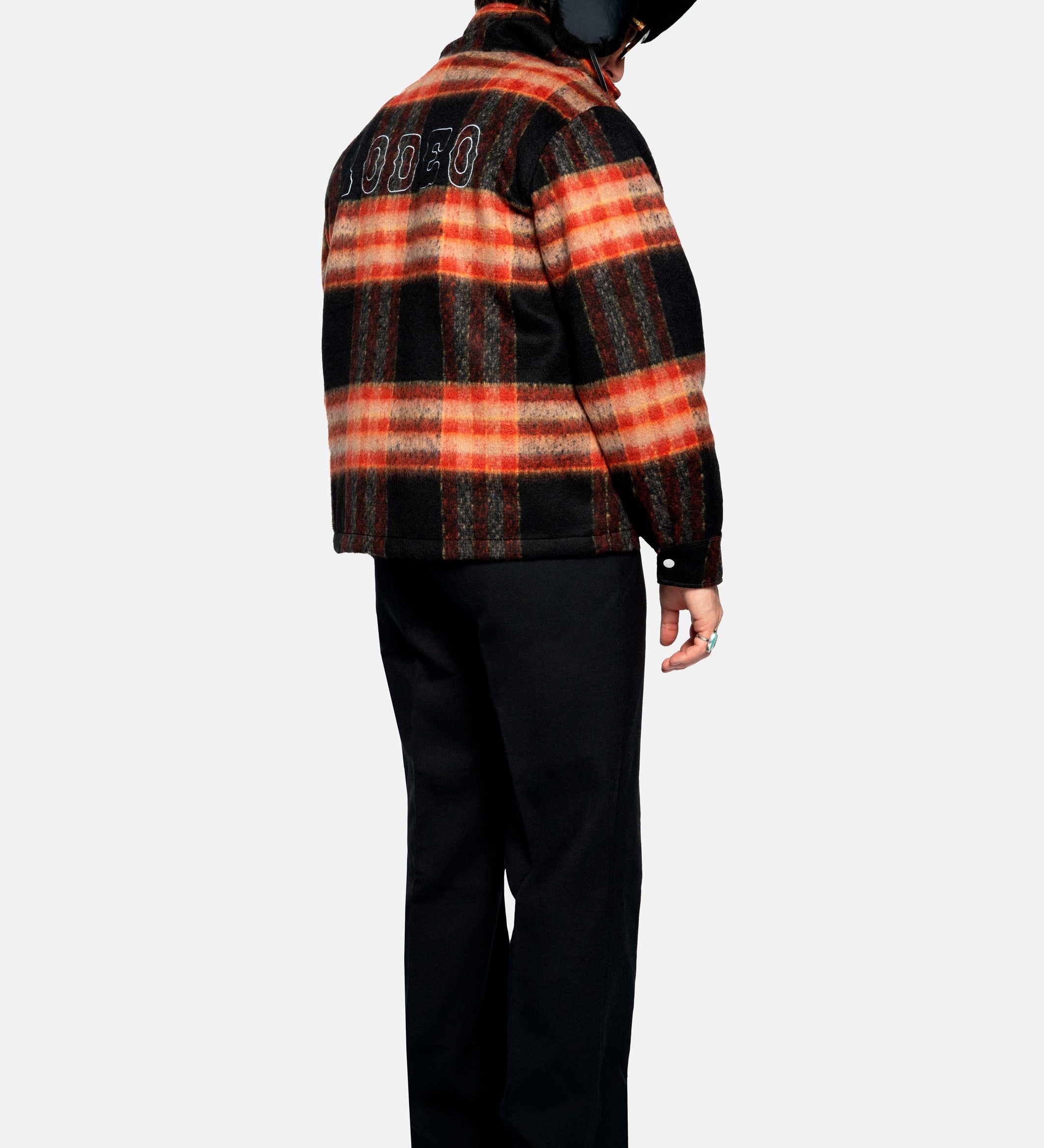 Back of male model wearing an orange red colored lumberjack jacket with pockets, full zipper and embroidered Nikben logo 