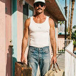 Male model wearing white ribbed tank top with black NB initials on chest