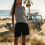 Female model wearing green ribbed tank top with white NB initials on chest