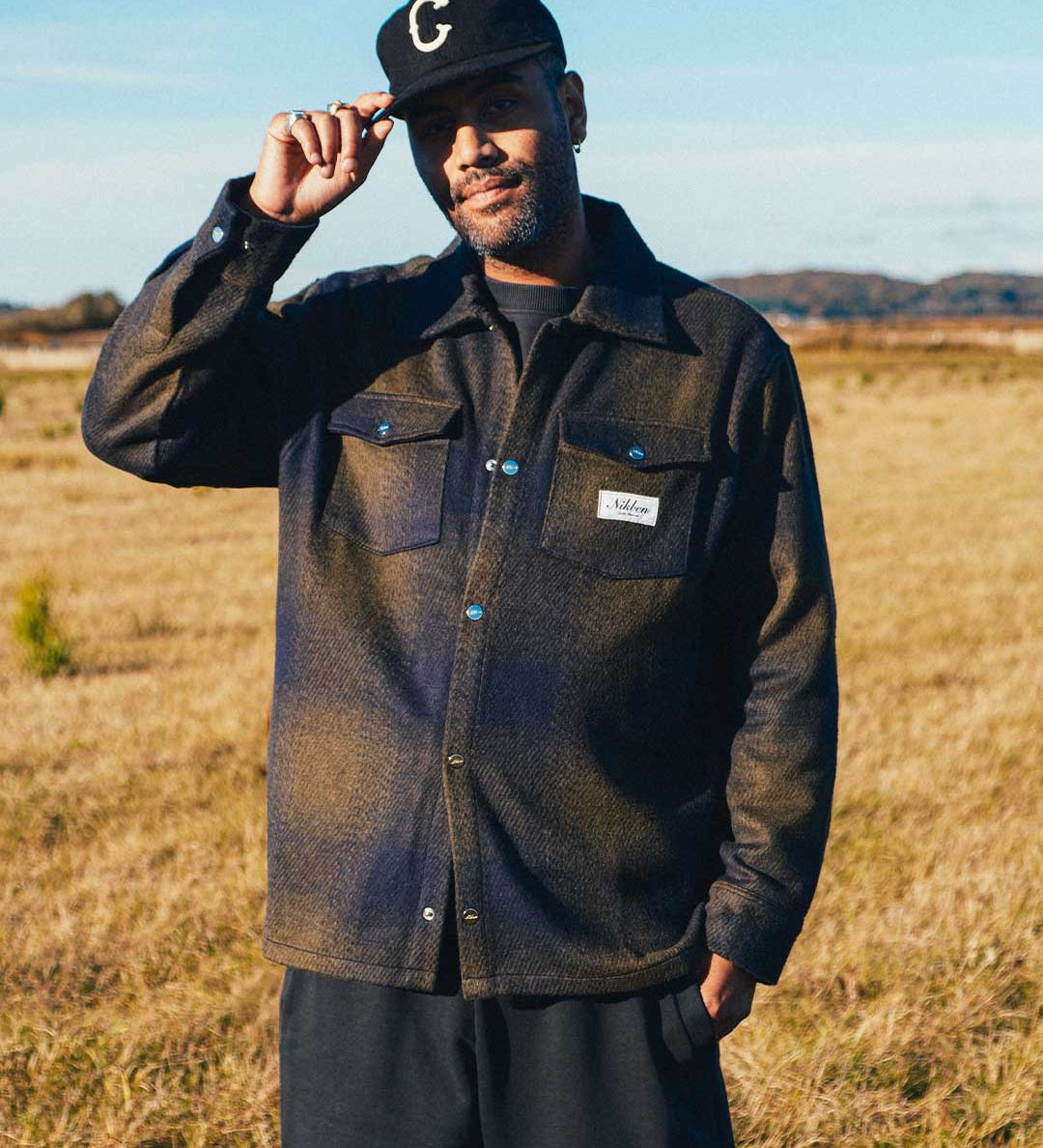 model wearing dark blue and green flannel overshirt with front pockets