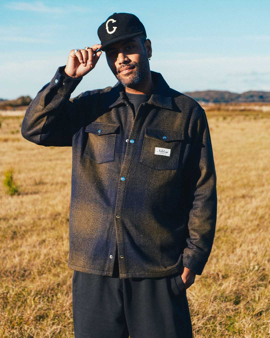 model wearing dark blue and green flannel overshirt with front pockets
