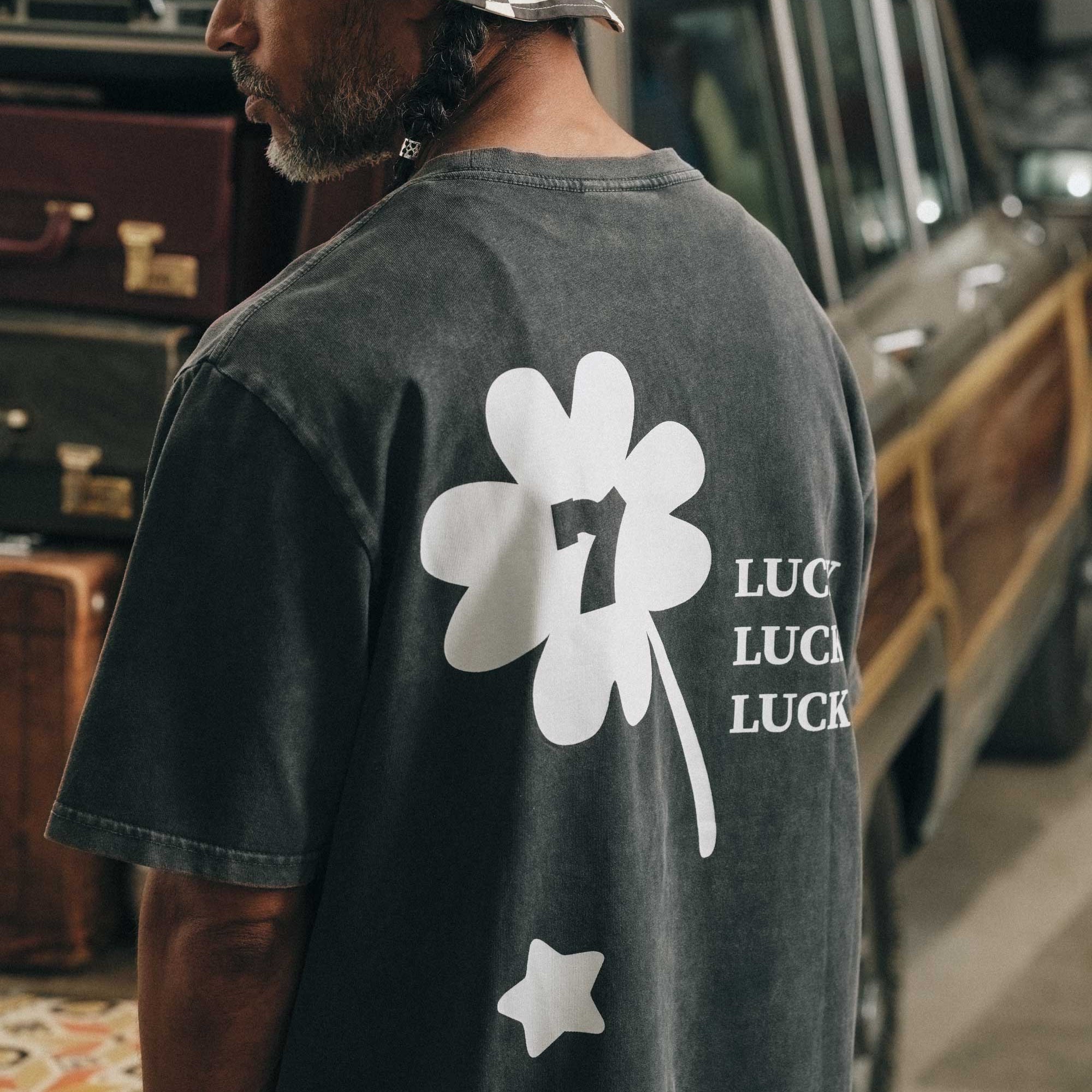 Back view of male model wearing a black t-shirt with white "Lucky" back print.