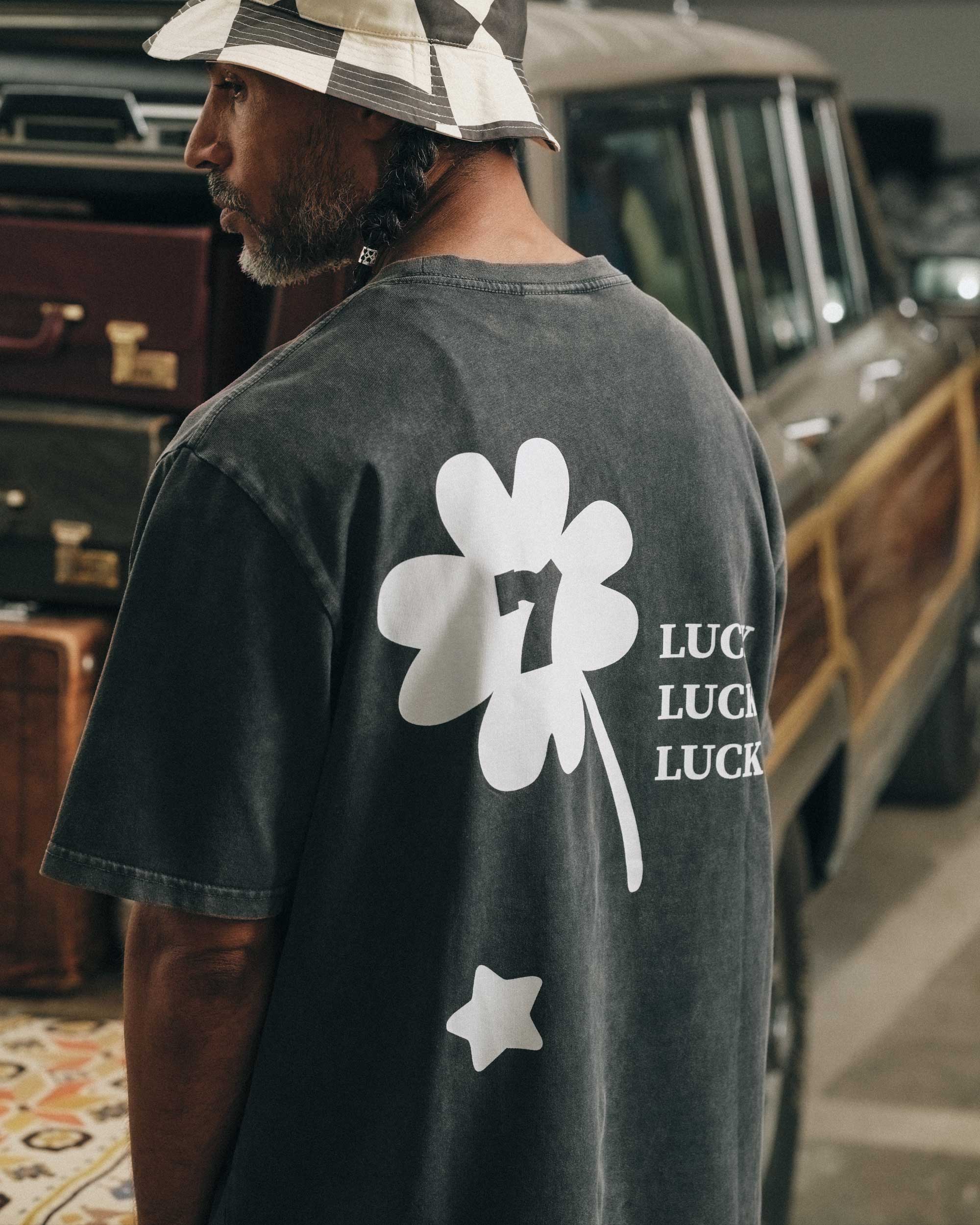Back view of male model wearing a black t-shirt with white "Lucky" back print.