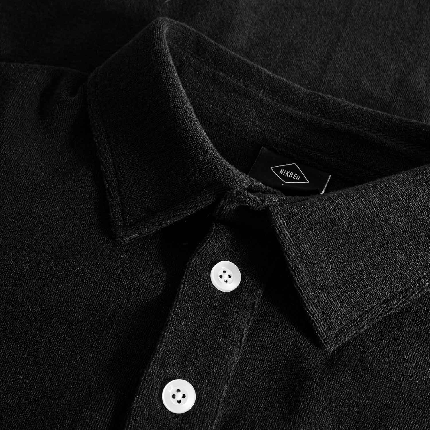 Close up on collar on a black kaftan in terry toweling fabric. 