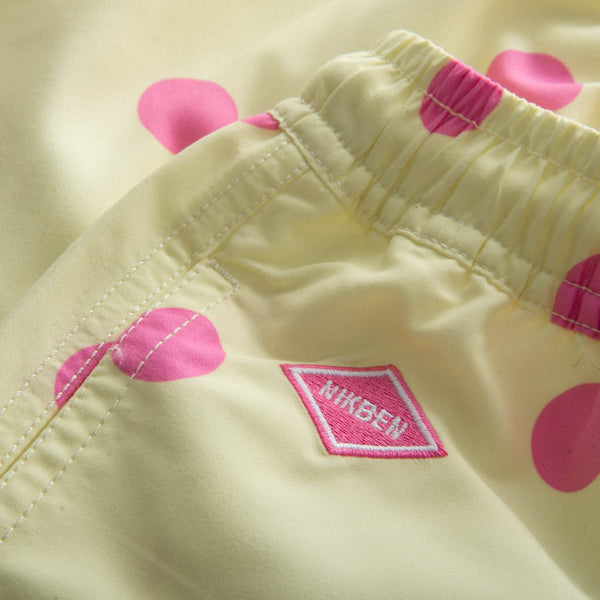 Pink logo on yellow kids swim trunks with pink dots
