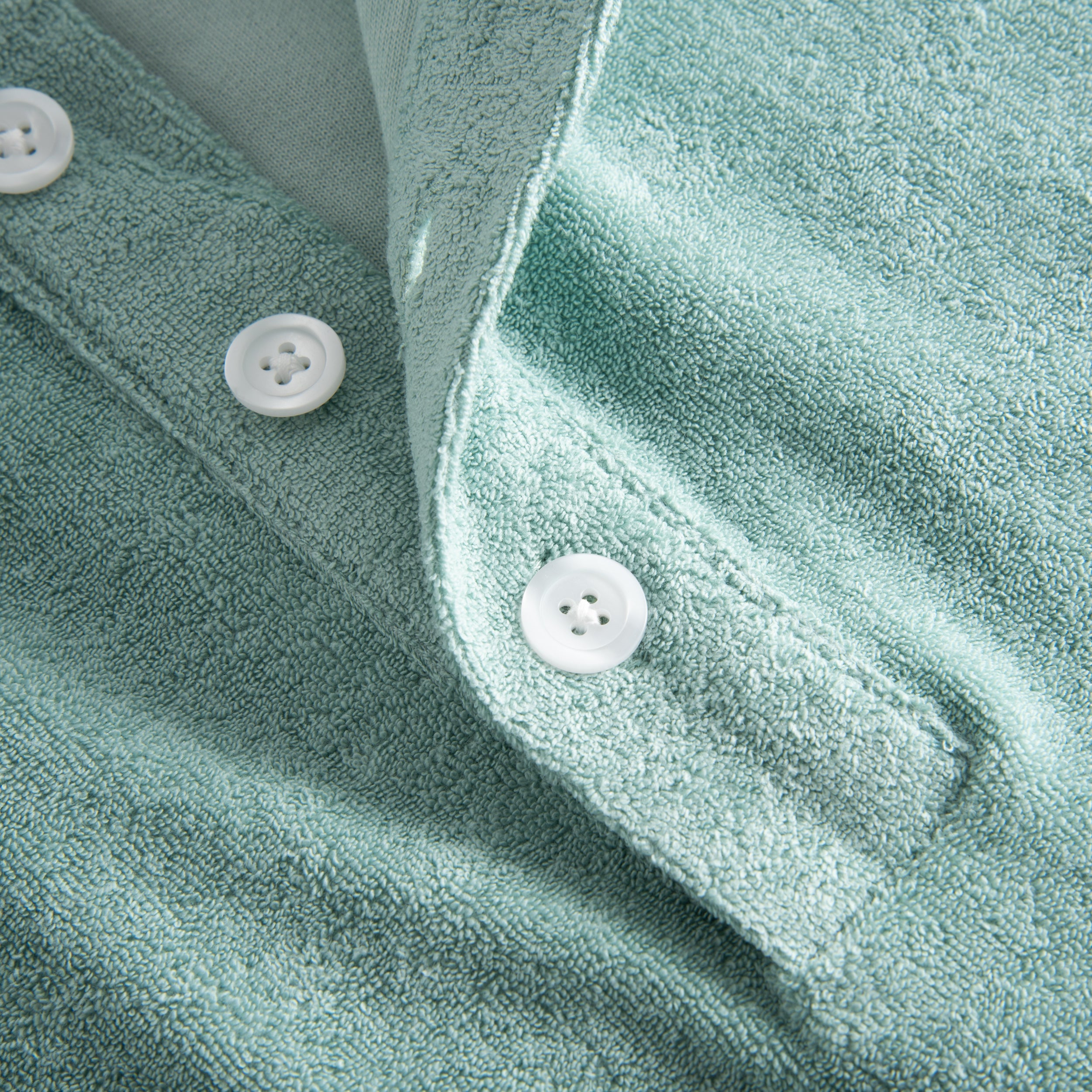 White buttons on green shirt in Terry toweling fabric