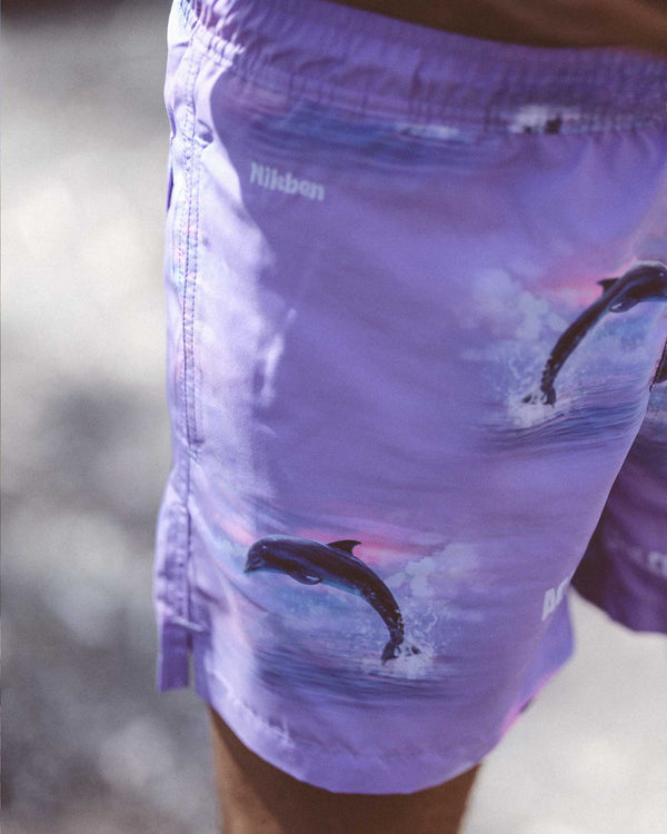 Purple swim trunks with dolphin print and white logo