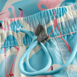 Drawstring on blue swim trunks with pink flamingo print