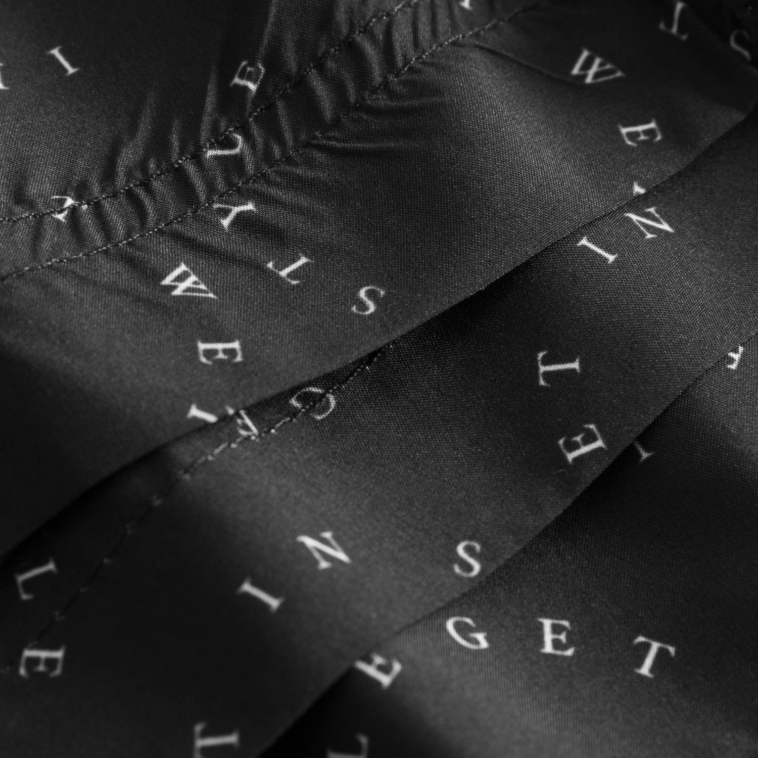 Close up on black swim trunks with white text