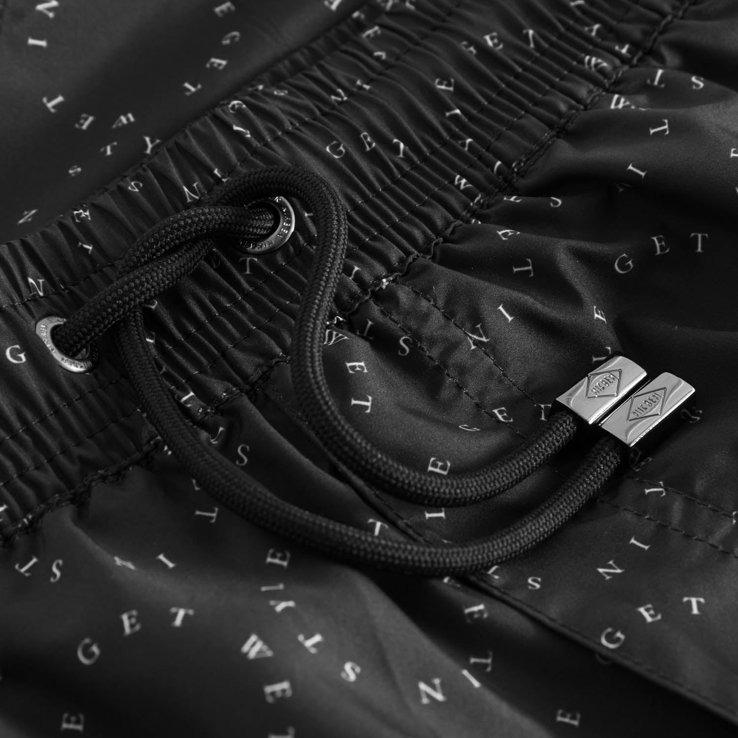 Drawstring waistband on black swim trunks with white text