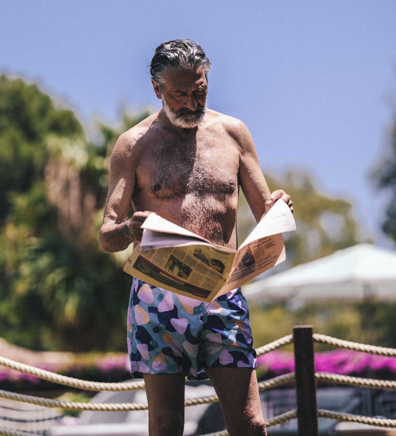 Man reading the news wearing swim trunks
