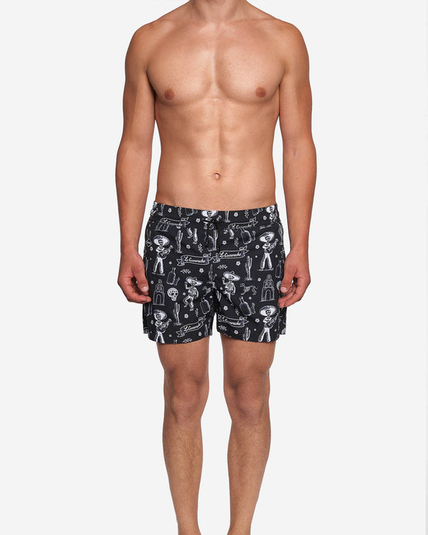 Model wearing black mid length swim trunks with white print