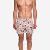 Model wearing beige swim trunks with multicolored safari print