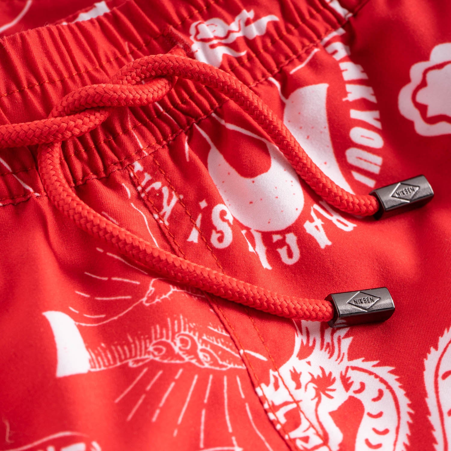 Drawstring waistband on red swim trunks with white print