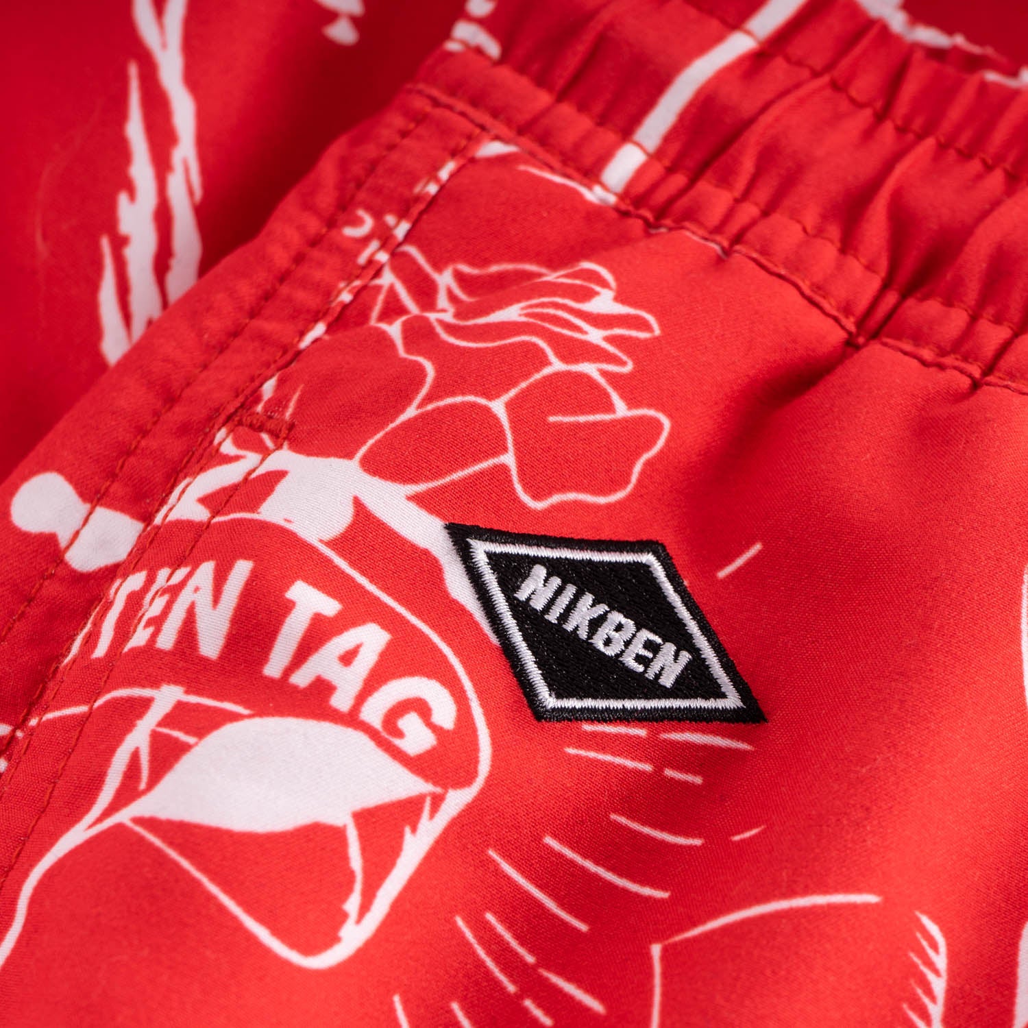 Black logo on red swim trunks with white print