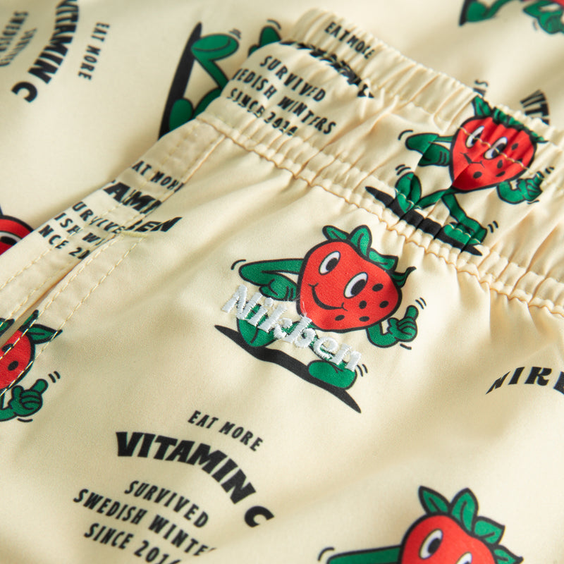 Close up of off white swim trunks with strawberries and text