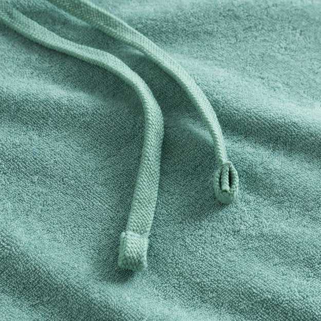 Close-up of drawstrings and fabric on a green Terry toweling hoodie.