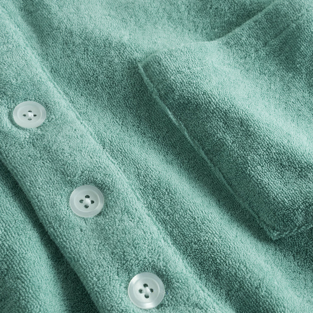 White buttons and chest pocket on green shirt in Terry toweling fabric