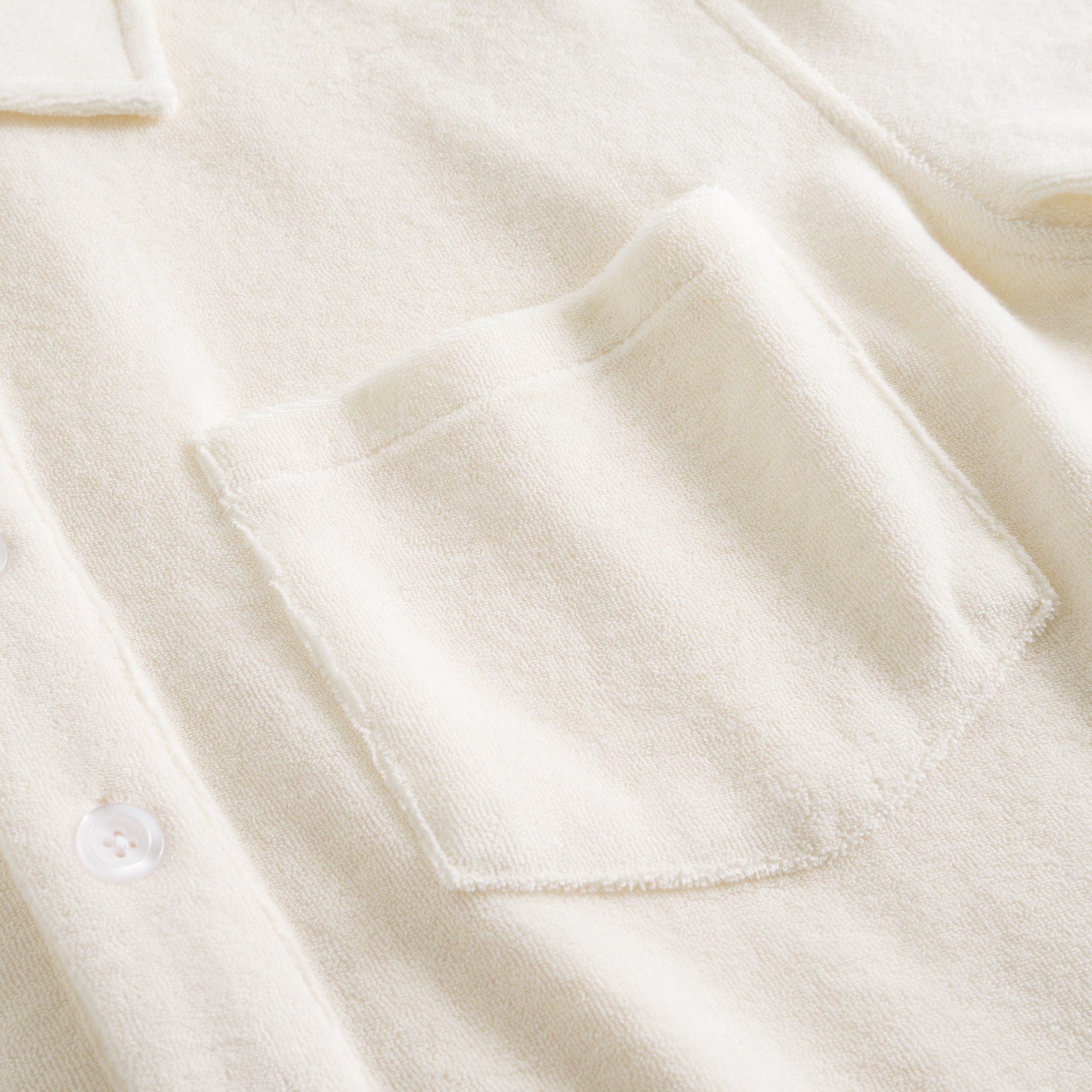 Close up on chest pocket on a white kaftan in terry toweling fabric