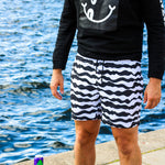 Model wearing black/white mid length swim trunks