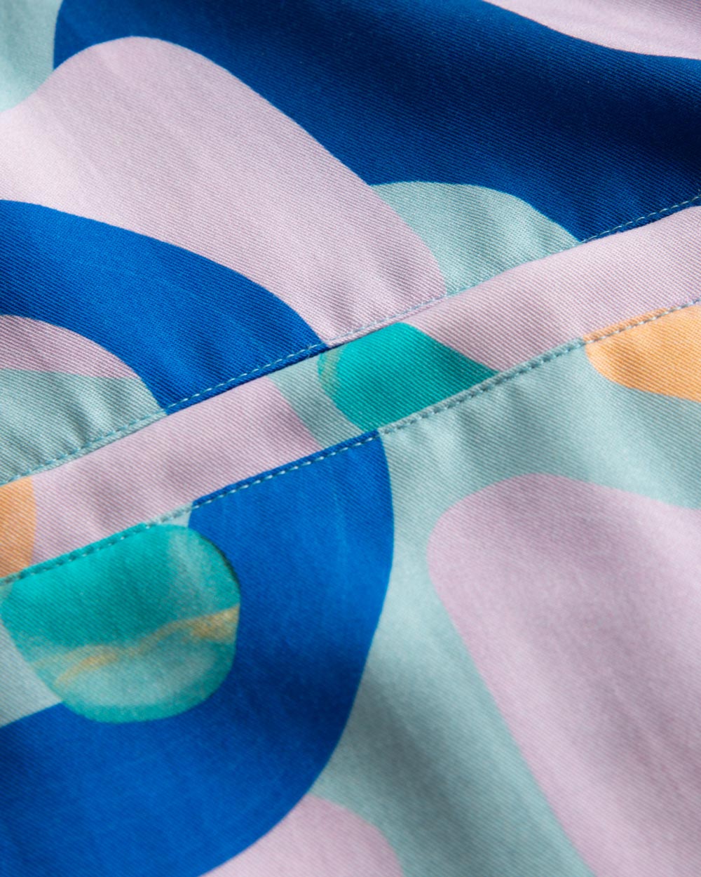 Close up view on breast pocket on a short-sleeved vacation shirt with a multi-colored graphic patter