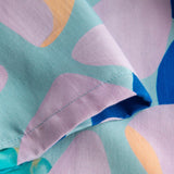 Close up view on stitchings on a short-sleeved vacation shirt with a multi-colored graphic patter