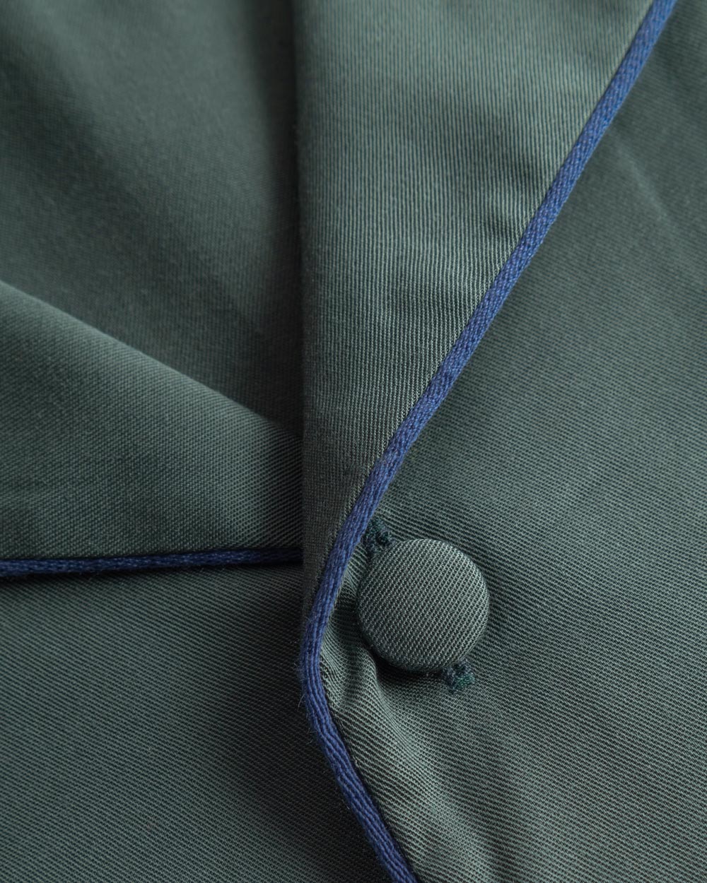 Close up on buttons and pipe linings on a green short-sleeved vacation shirt