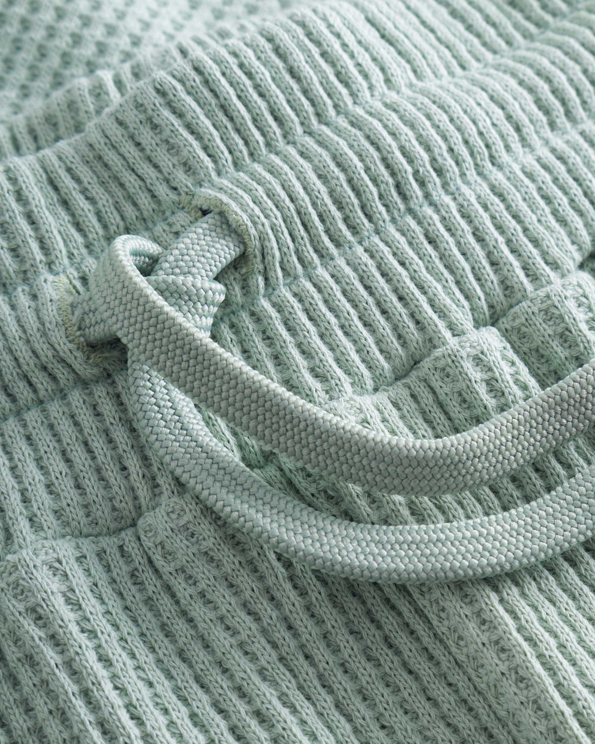 Close up of drawstring on mint green waffle-patterned short-length shorts.
