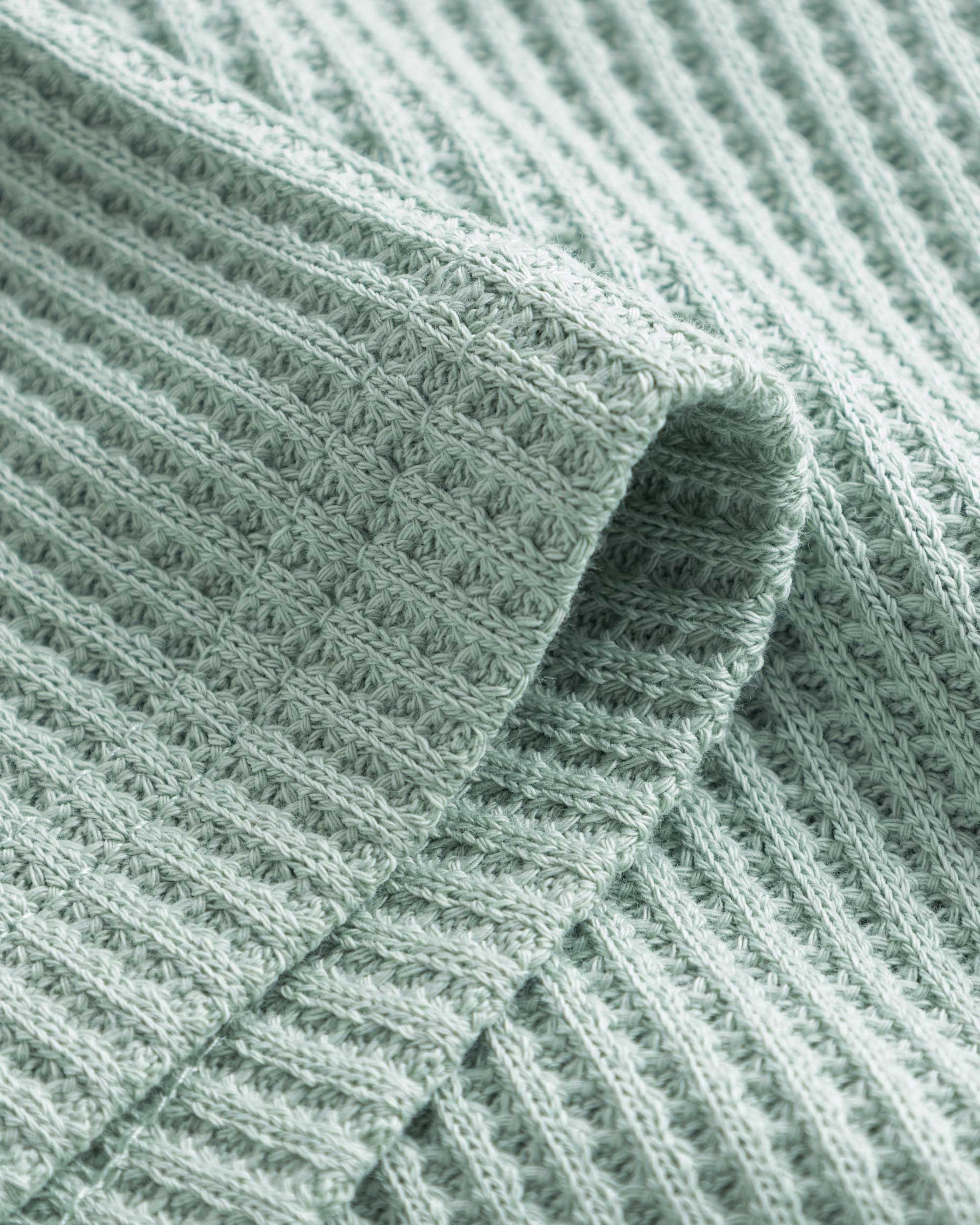 Close-up of stitchings and sleeve on a mint green waffle-patterned shirt.