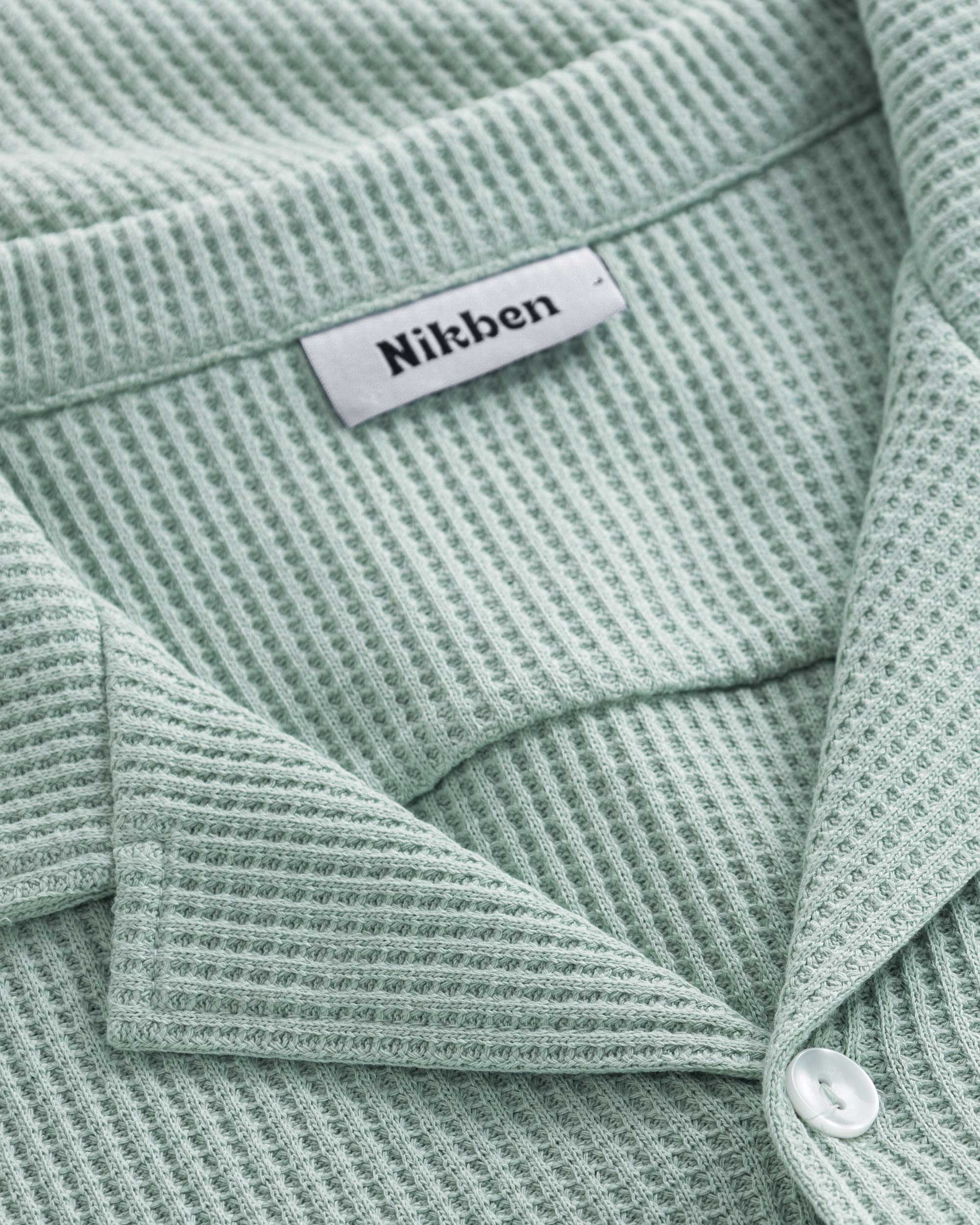 Close-up of open collar on a mint green waffle-patterned shirt.
