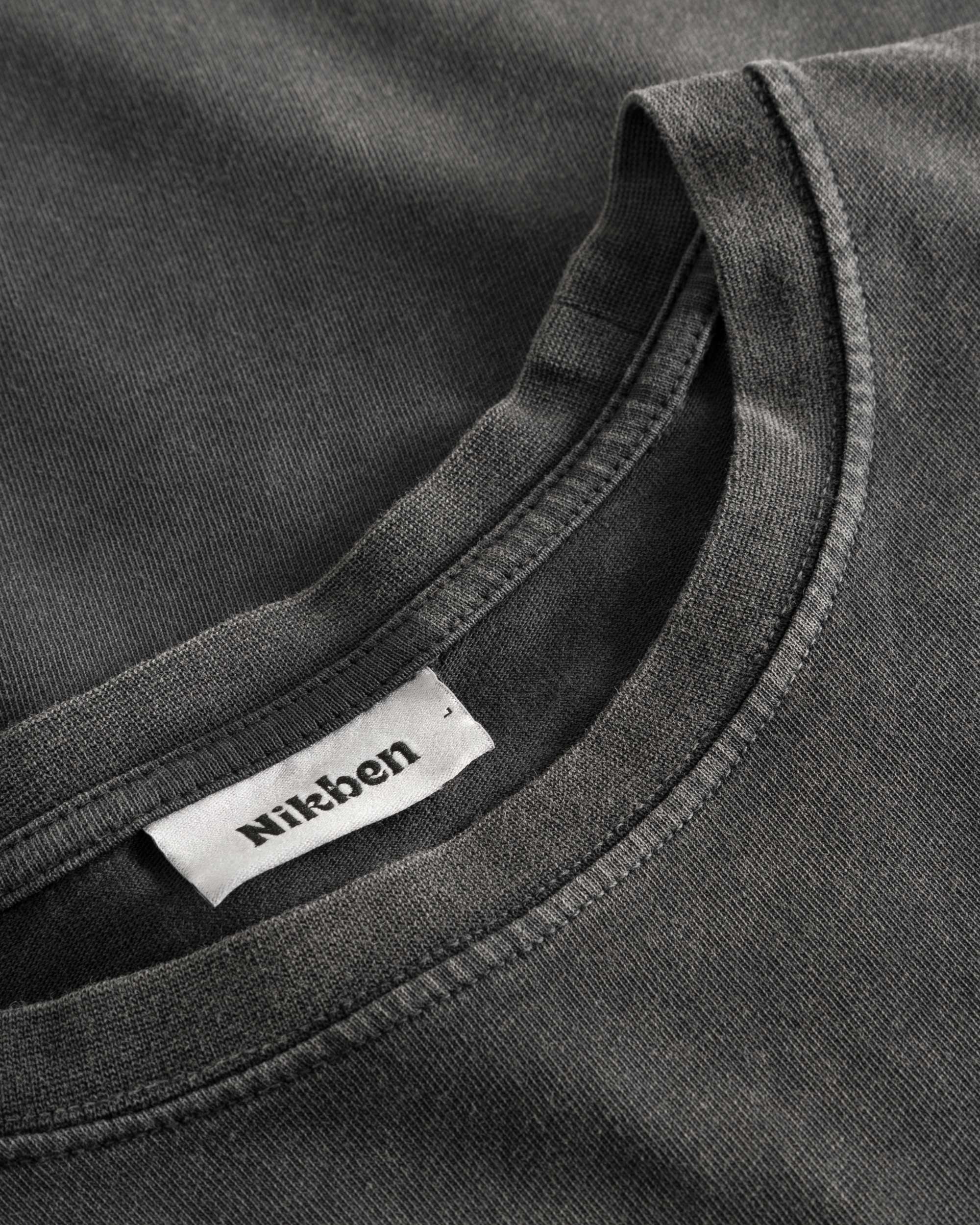 Close-up view of the round neck and stitchings on a washed black t-shirt
