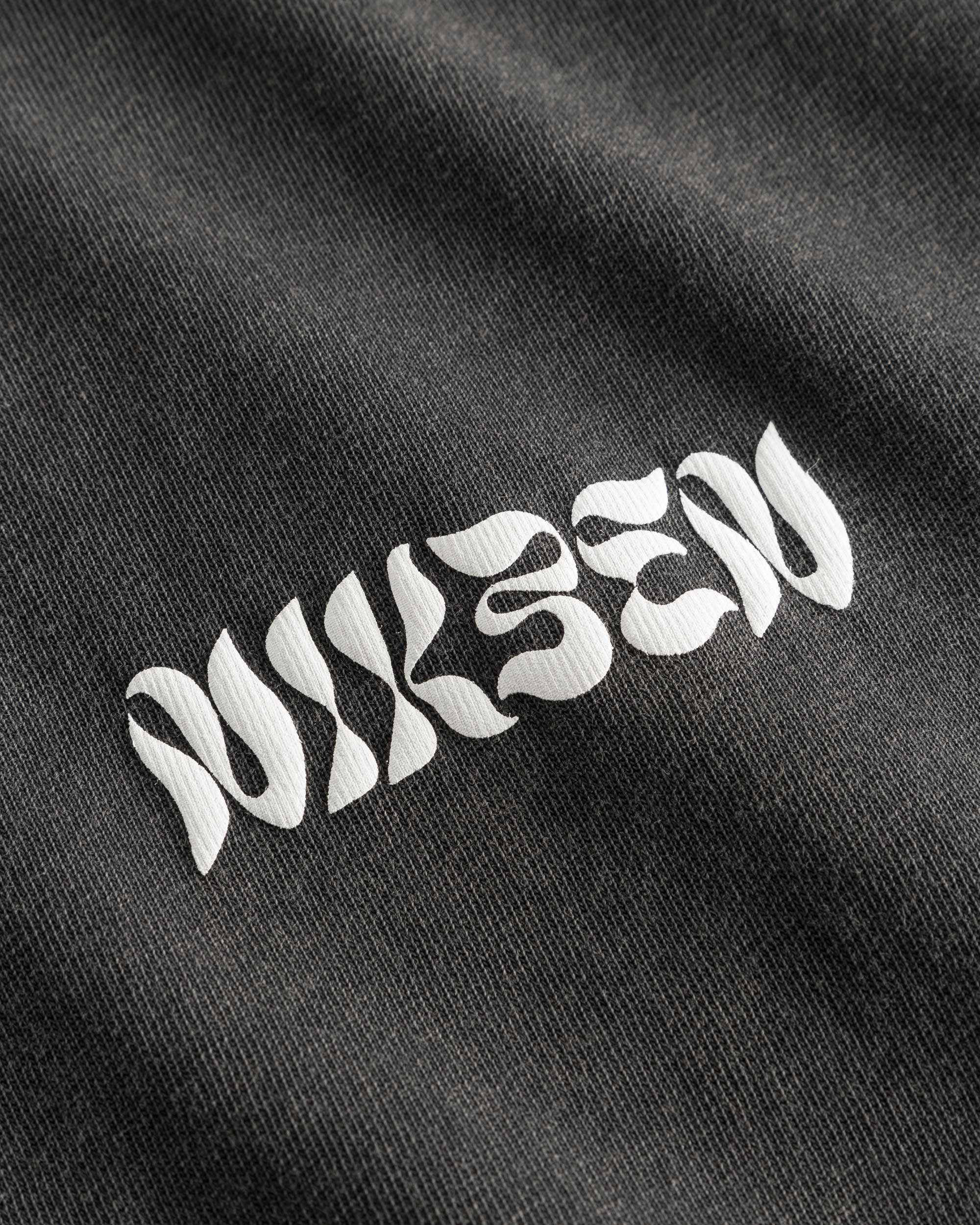Close up of white text logo on washed black t-shirt