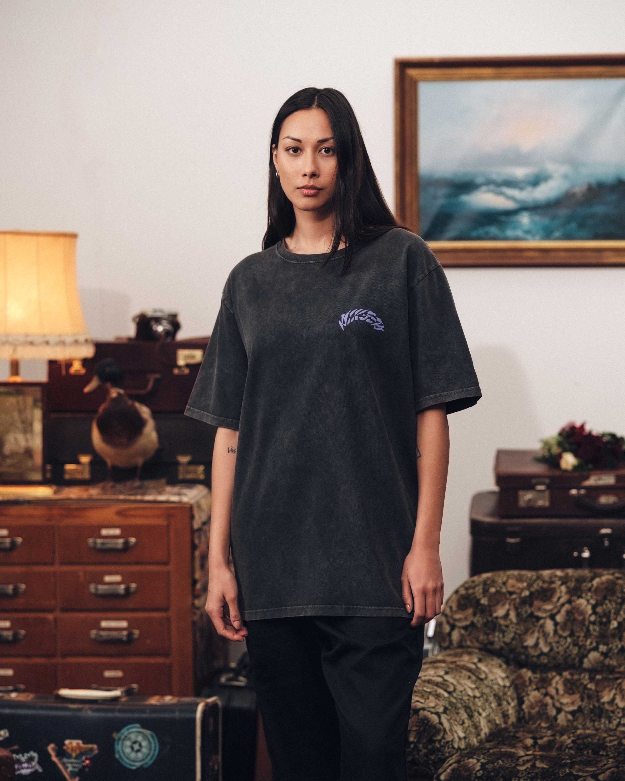 Female model wearing a washed black t-shirt with purple "Nikben" logo on chest.