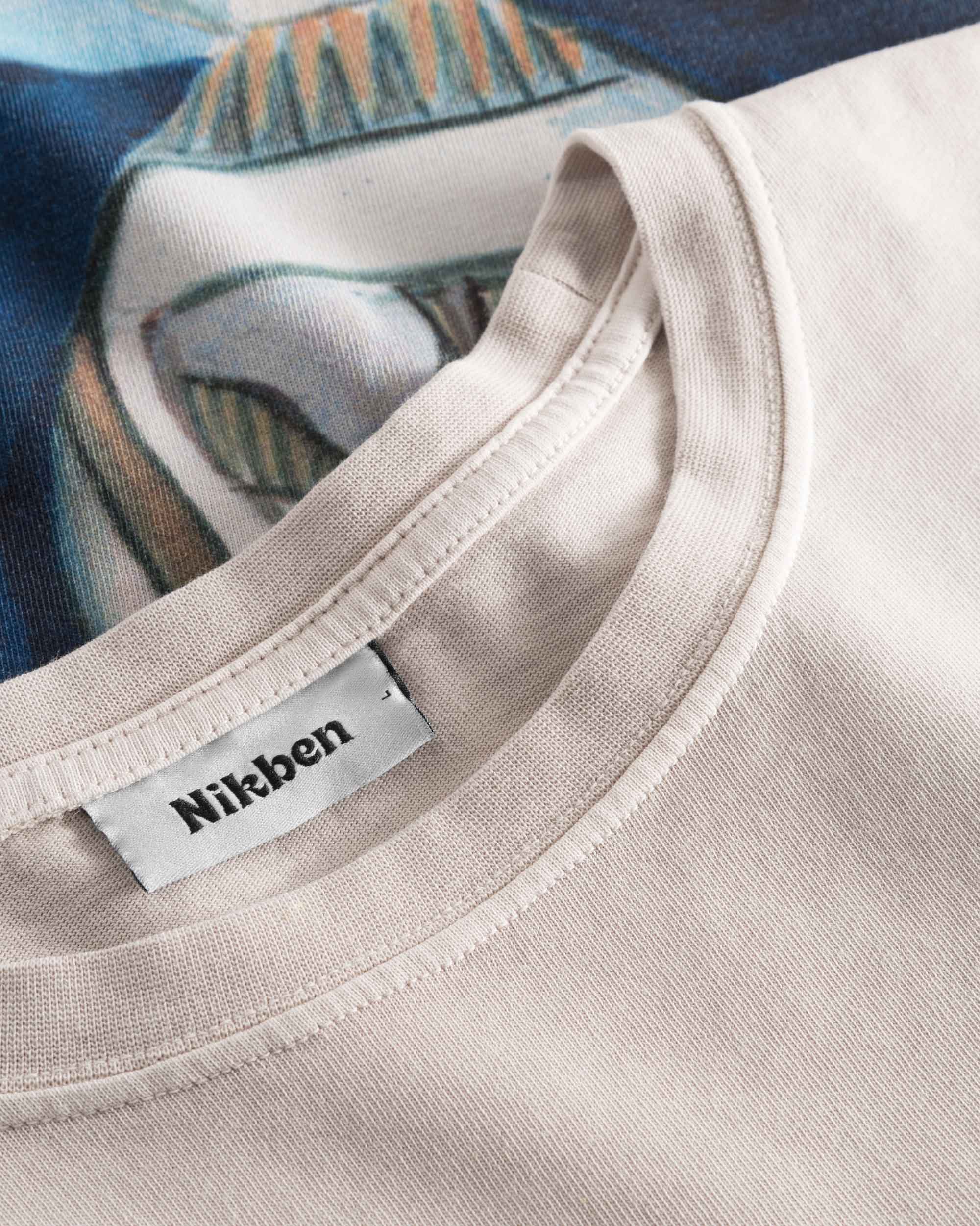 Close-up view of the round neck and stitchings on a creme and blue colored t-shirt