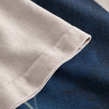 Close-up view of the sleeve and stitchings on a creme and blue colored t-shirt