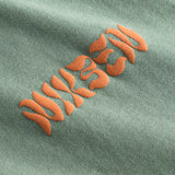 Orange puffy "Nikben" logo on a green t-shirt.