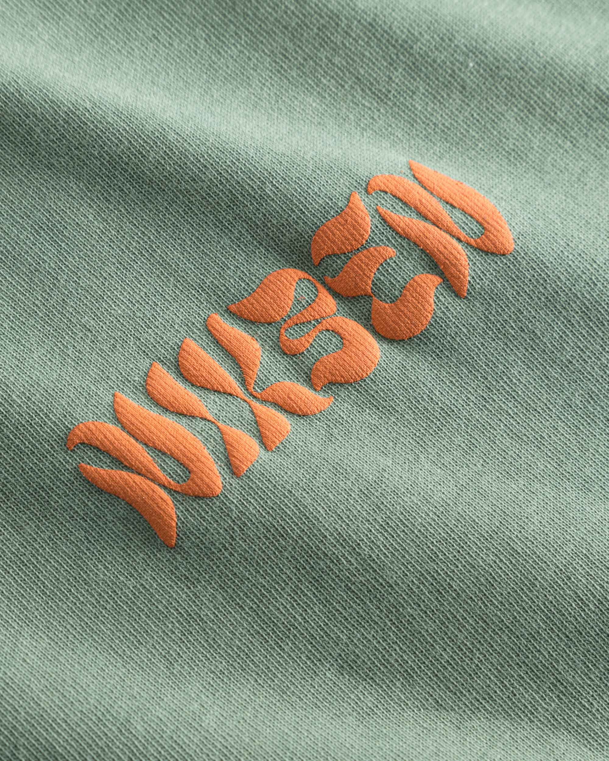 Orange puffy "Nikben" logo on a green t-shirt.