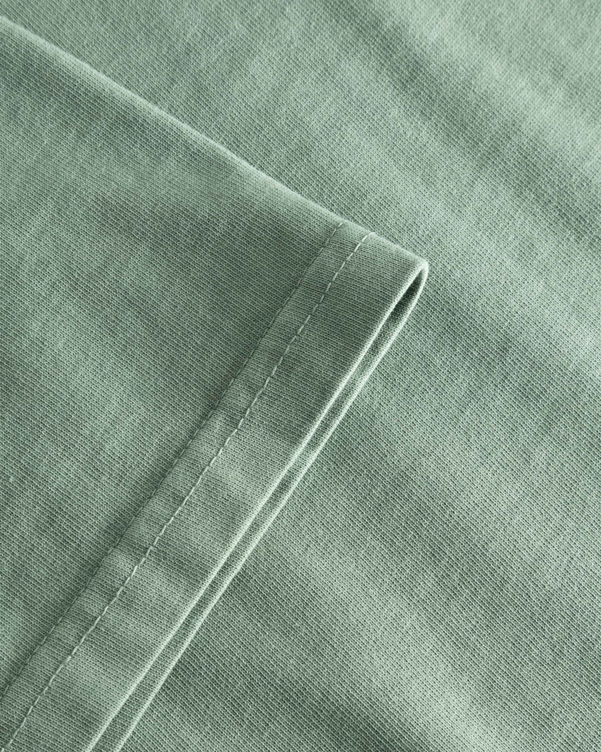 Close-up view of the sleeve and stitchings on a green t-shirt
