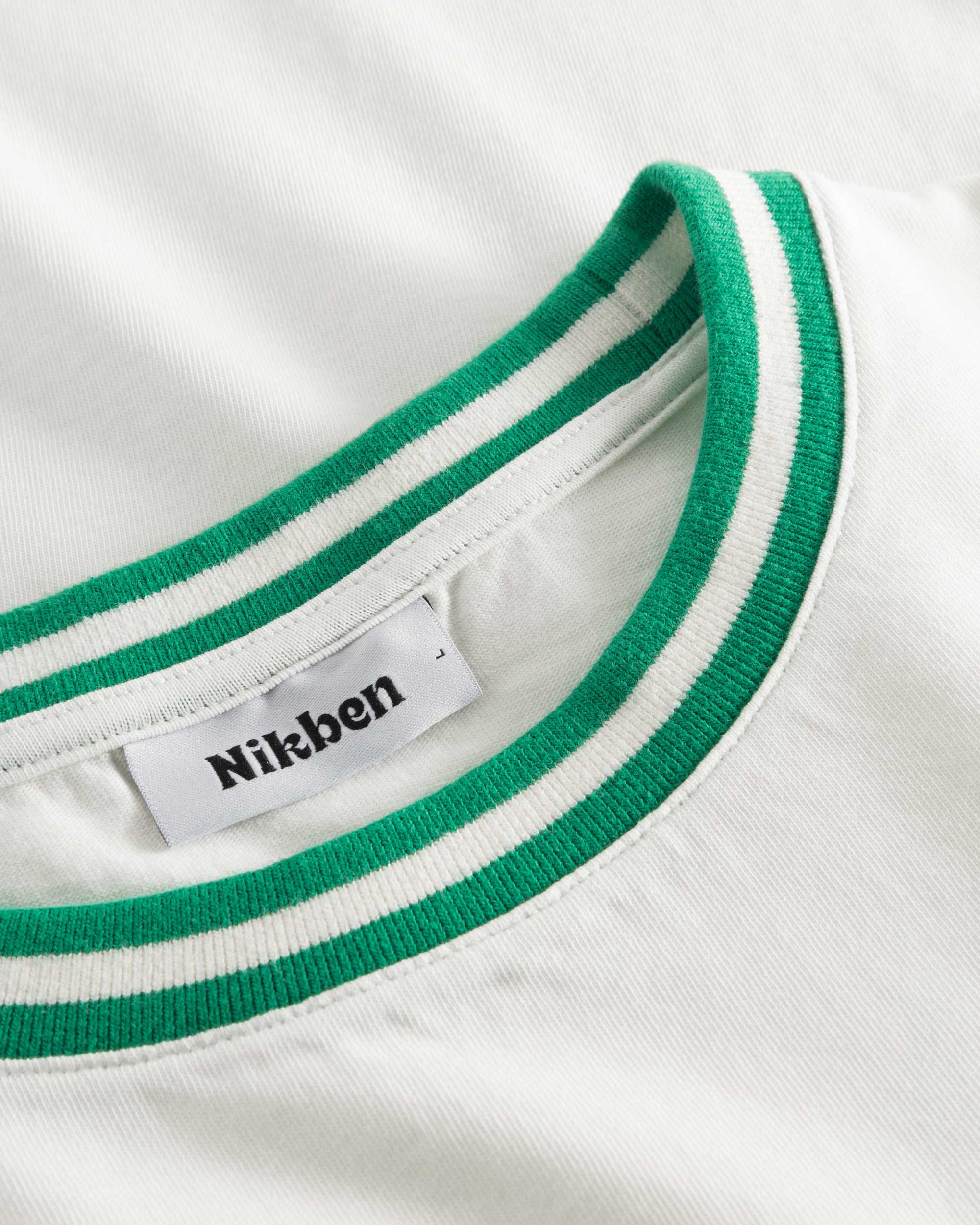 Close-up of round neck and stitching on white/green T-shirt