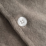 Close up of white pearl button on a dark grey short sleeve shirt.