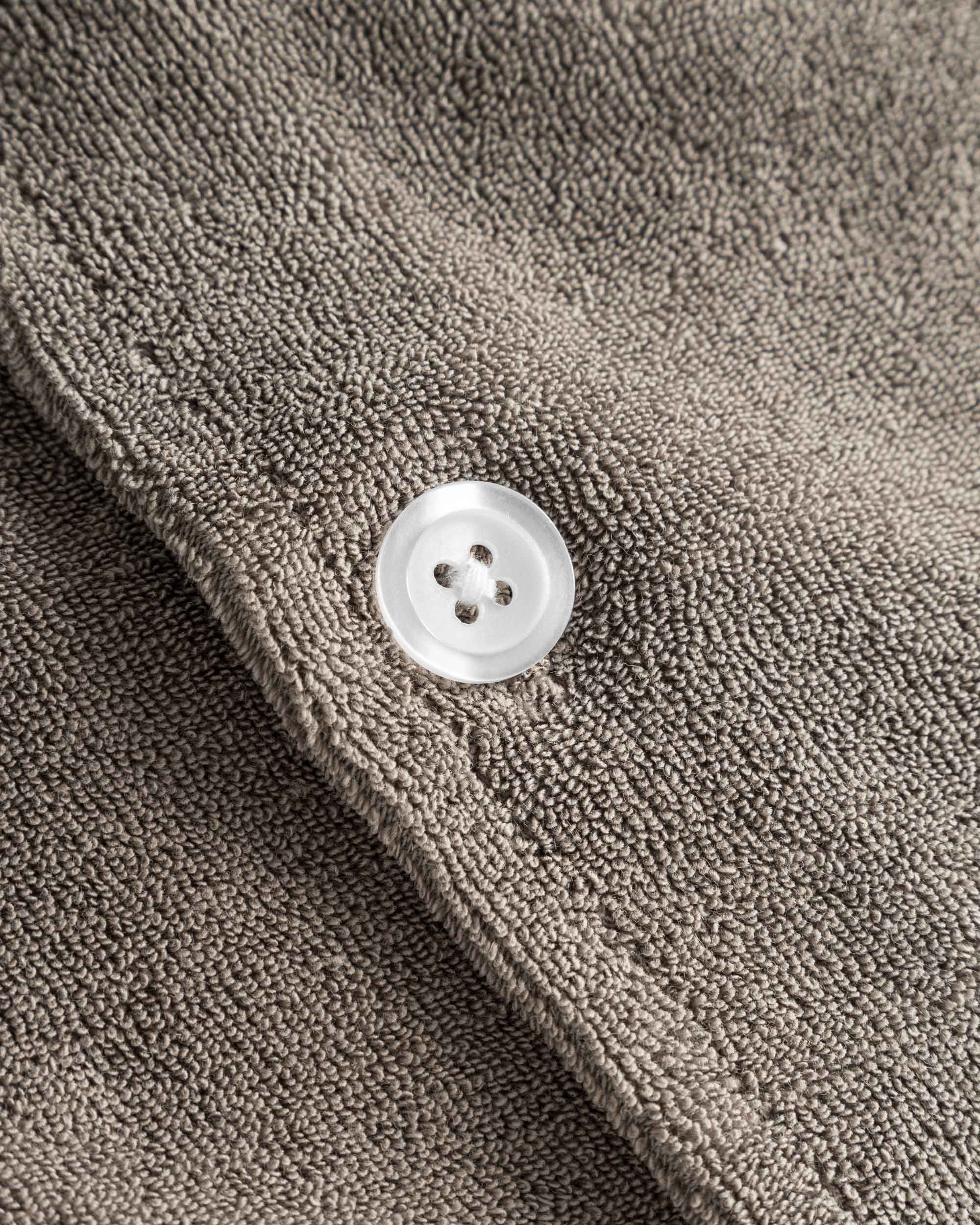 Close up of white pearl button on a dark grey short sleeve shirt.
