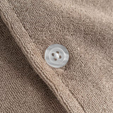 Close up of white pearl button on a light brown short sleeve shirt