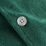 Close up of white pearl button on a green short sleeve shirt.