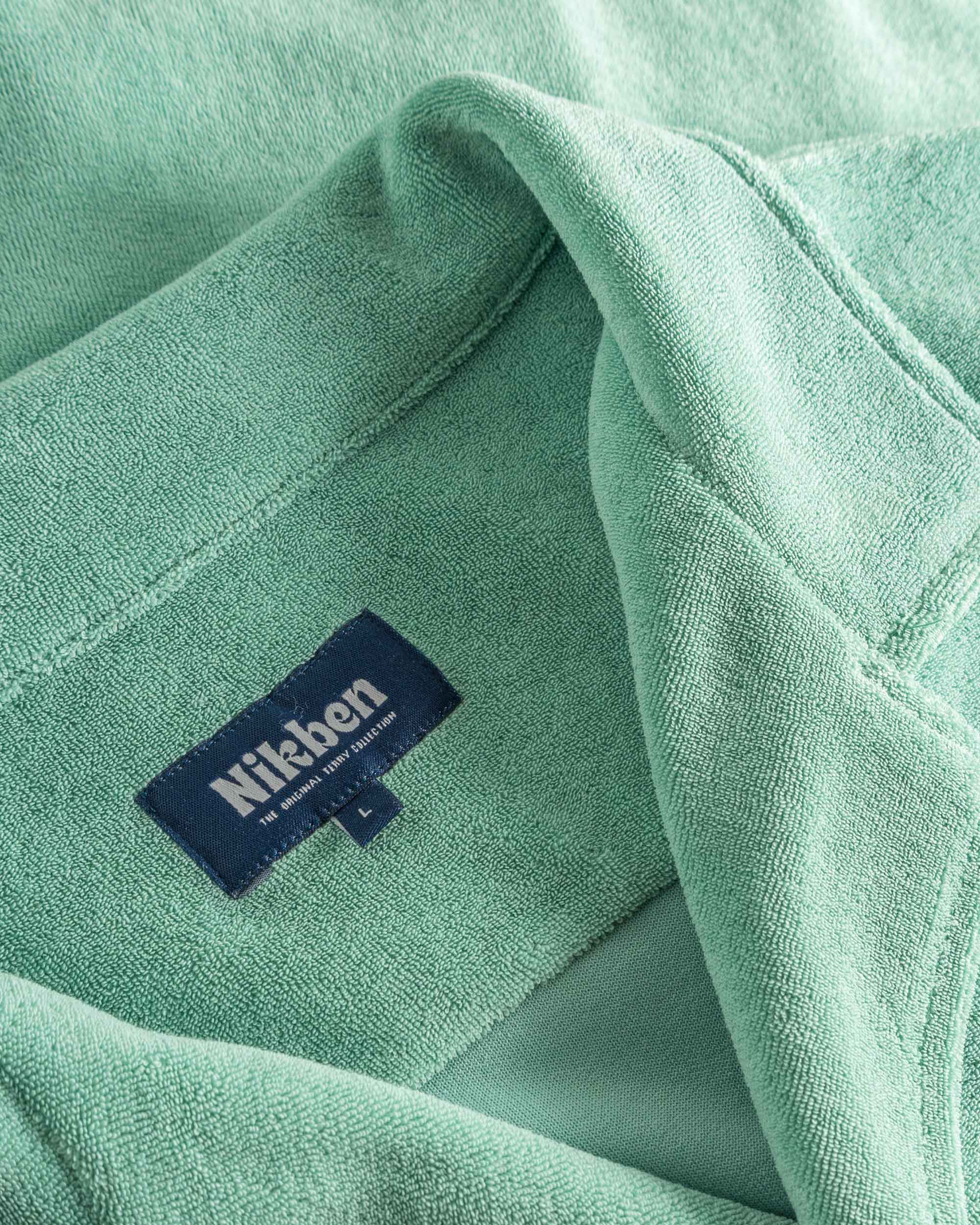 Close up of open collar and tag on a grey-green short sleeve shirt