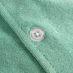 Close up of white pearl button on a grey-green short sleeve shirt.