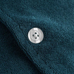 Close up of white pearl button on a navy blue short sleeve shirt.