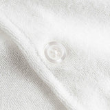 Close up of white pearl button on an off white short sleeve shirt.