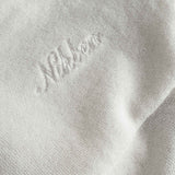 Close up of embroidered script on a white and brown short sleeve shirt